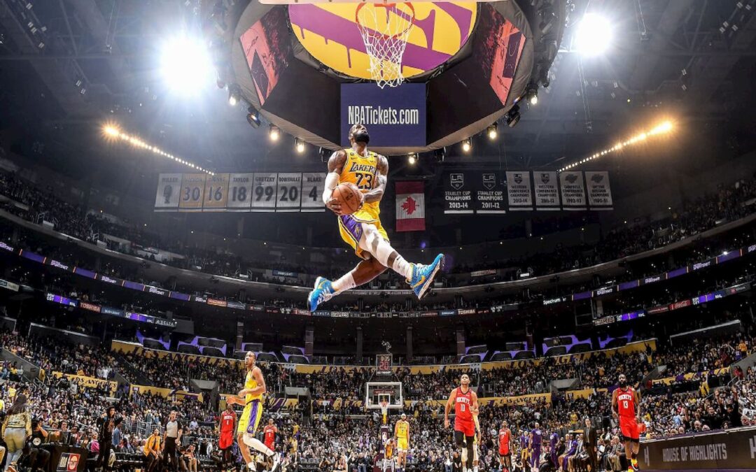 imagem panorâmica de Lebron James usando uniforme amarelo e roxo do Lakers se preparando para enterrar bola da cesta durante partida