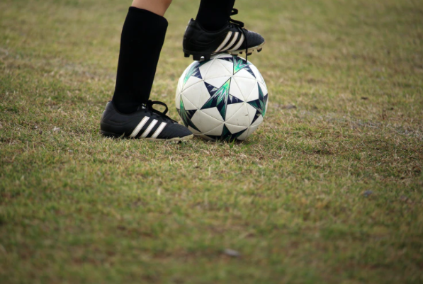imagem ampliada dos pés de um jogador apoiando um dos pés em cima da bola de futebol