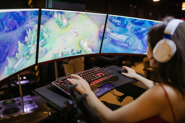 Mulher diante de várias telas de computador com o jogo League of Legends